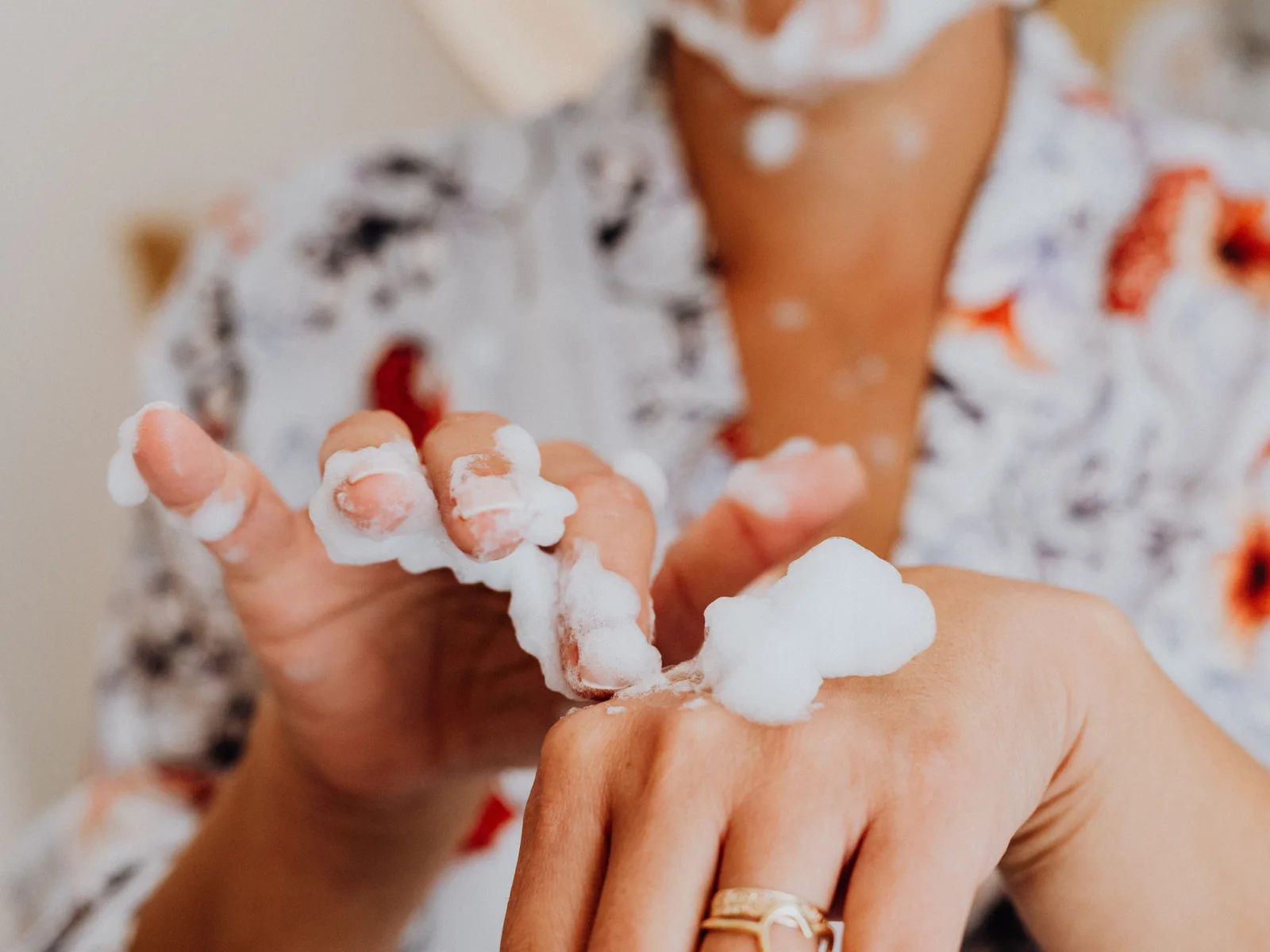 Une main tient la mousse d’un nettoyant devant un visage